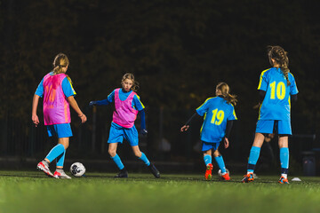 Fototapeta premium teenage Caucasian girls playing football at the late evening practice, full shot, teenage lifestyle. High quality photo