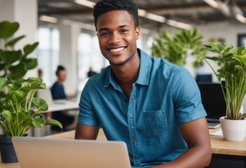 Smiling man using laptop with indoor plants around. Green and productive office environment.