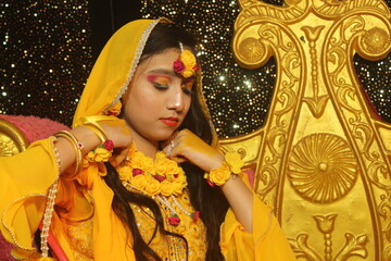 Portrait of a beautiful female model in yellow saree with light makeup and jewelry made of flowers. Its a wedding dress and makeup of Indian bride for Haldi function.