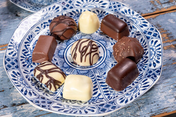 Variety of luxury belgian chocolate pralines bonbons on blue china porcelain plate, tea time