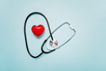 stethoscope with its tubing creating heart shape around red heart model on Pale Blue Background symbolizing love and care in the medical field.