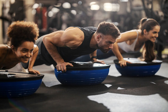 Sportspeople doing workouts with bosu ball in a gym.