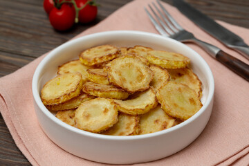 Slices of fried crookneck in oil with garlic on a wooden background
