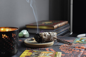 A close up image of a burning white sage smudge stick and healing crystals. Witchcraft, meditation, healing sage.