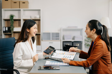 Businesswoman leading team meeting and using tablet and laptop computer with financial in co working office