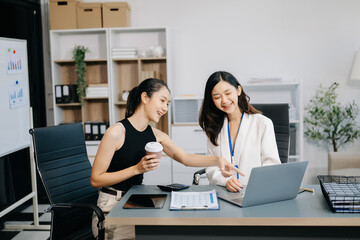 Businesswomen work and discuss their business plans. A woman employee explains and shows her colleague the results paper