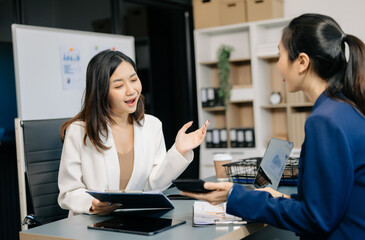 Two business workers talking on the smartphone and using laptop at the office..