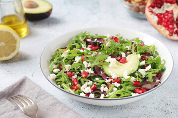 A plate with green rocket salad with pomegranate and avocado	