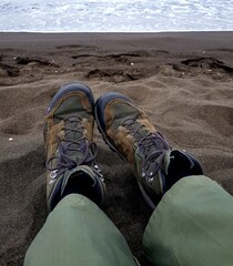 A pair of trekking shoes on the sand of a beach.