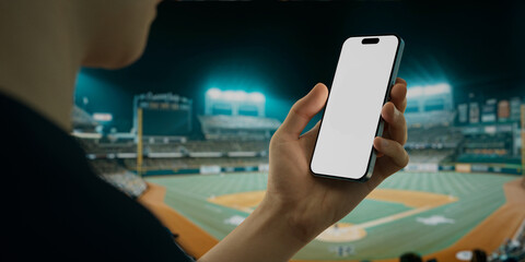 A hand holds a smartphone with a green screen at a baseball stadium - 757094381