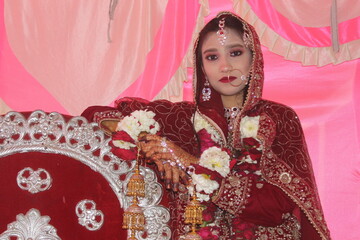 Pretty girl in traditional Indian Pakistani bridal costume with heavy makeup and jewellery, selective focus with blur in image

