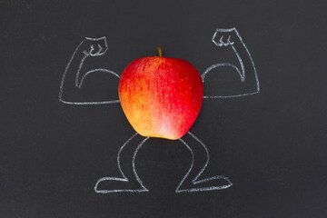 Red apple with muscular arms drawn with chalk on blackboard,  creative, funny healthy lifestyle concept 