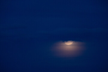 Magical full moon at night. Telephoto view of mysterious clouds flying against the bright full...