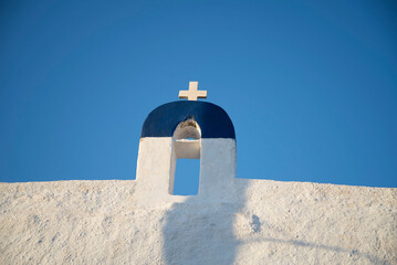 White bell tower top with a cross against a blue sky