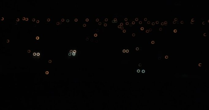 Bokeh circular out of focus car headlights pass around a curve at night in the city of Quebec.