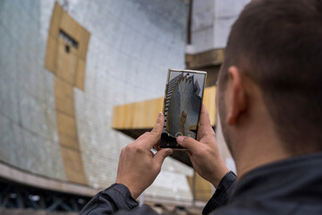 Man capturing a reflection of an angular building on his phone