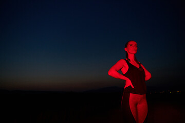 Fototapeta na wymiar Athlete Strikes a Pose in Red-Lit Nighttime Glow