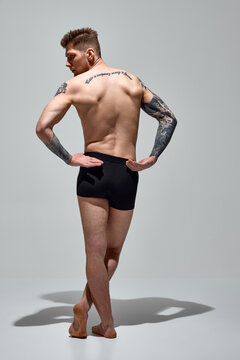 Rear view portrait of man in underwear holding hands behind back showing his muscular spine against grey studio background. Copy space. Concept of natural beauty, fashion and style, male health. Ad