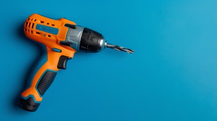 A drill rests on a smooth blue surface, waiting to be picked up and put to use - obrazy, fototapety, plakaty