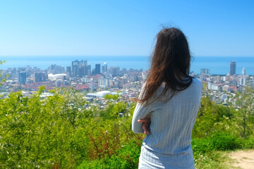 Woman tourisy admiring cityscape of Batumi city from mountain in sunny day. Coastal city in...