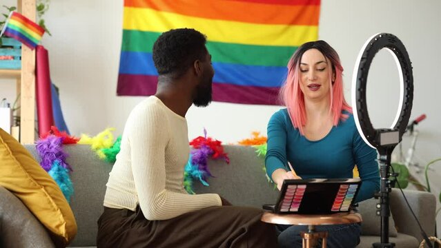 young friends recording a live beauty tutorial for social media with gay pride themed makeup - LGBTQ+