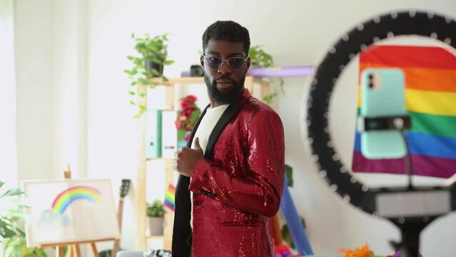 handsome and happy young adult african american man in sequin blazer records himself dancing live for social media before pride party - LGBTQ concept