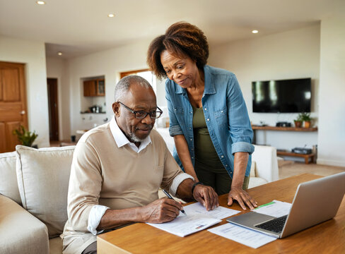 Senior African American Couple Collaborating on Documents with a Laptop on the Desk