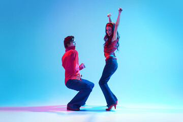 Rockability era. Retro dance aesthetics. Young stylish man and woman dancing against blue...