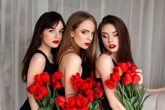 Pretty, nice, charming, successful trio of girls in dresses with make up, having red tulips in hands, looking at camera, celebrating 8-march, women's day, hen party or birthday