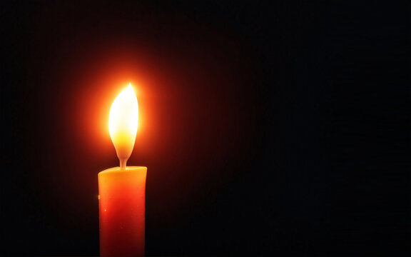 Burning candle glowing in the dark. Copy space in the right for the text. Candle with dark background.