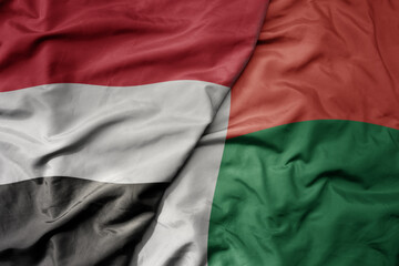big waving national colorful flag of madagascar and national flag of yemen .