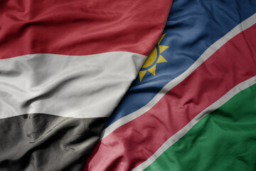 big waving national colorful flag of namibia and national flag of yemen .