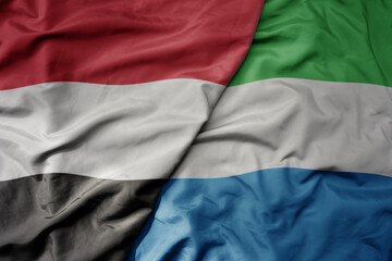 big waving national colorful flag of sierra leone and national flag of yemen .