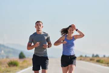 Energized by the beauty of nature, a couple powers through their morning run, their bodies and...