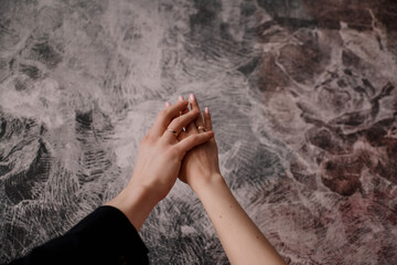 hands of a man and a woman with wedding rings on an abstract background