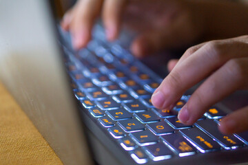 Close up image of hands typing on laptop computer keyboard and surfing the internet at home....