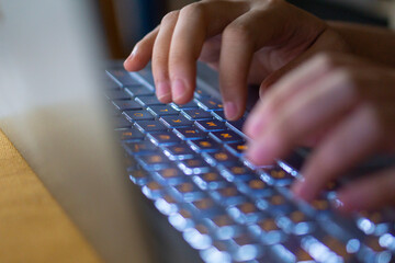 Close up image of hands typing on laptop computer keyboard and surfing the internet at home....