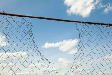 Fotobehang Broken metal mesh fence © rootstocks