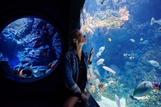 Young woman looking at fishes in oceanarium
