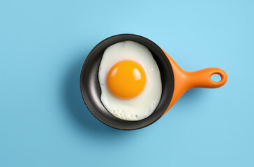 Creative food concept with fried egg on pan over yellow background. Top view. Creative pattern in minimal style. Flat lay. Square crop