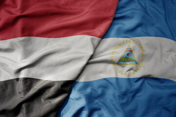 big waving national colorful flag of nicaragua and national flag of yemen .