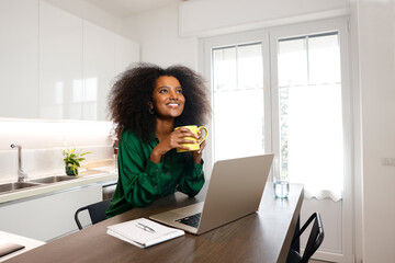A bright face and happy African American afro woman drinking coffee during break on her work at...