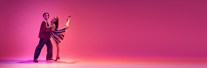 Retro dance aesthetics. Elegant young man and woman dancing against pink background in neon light....