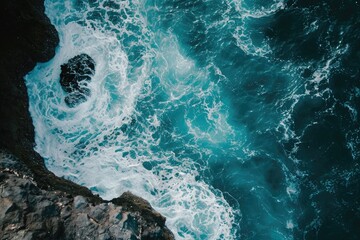 This breathtaking aerial photo captures a vast expanse of calm blue water, providing a serene view from above, A mesmerizing aerial display of a sea dancing around the rocky beach, AI Generated