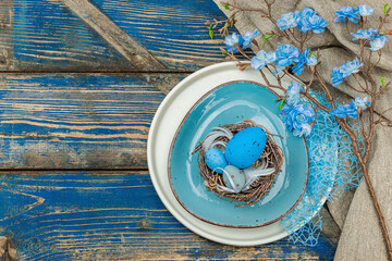 Easter table setting with eggs, bird's nest and blooming branch. Traditional festive symbols
