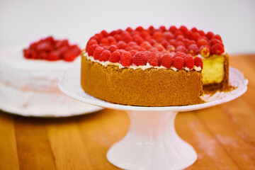 Stand, slice and cheesecake with cream and raspberries on table for sweet snack for tea time at home. Bakery, catering and gourmet dessert with crust, frosting and fresh organic fruit in dining room.
