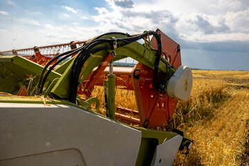 Close up view of combine harvester pouring a tractor-trailer with grain during harvesting