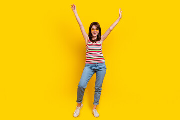 Fototapeta na wymiar Full size photo of optimistic cute woman dressed knitwear top jeans pants in sunglass raising hands up isolated on yellow color background