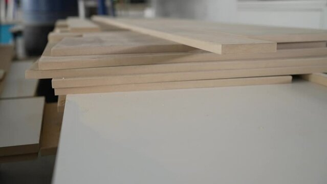 Material for the manufacture of furniture parts. A stack of white MDF panels lies on the floor. Material for the production of furniture, panels. Veneered chipboard in a furniture production warehouse