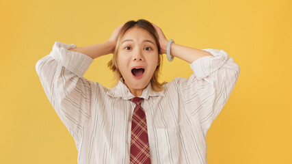 Surprised young woman dressed in shirt and tie, expressing happiness isolated on yellow background...